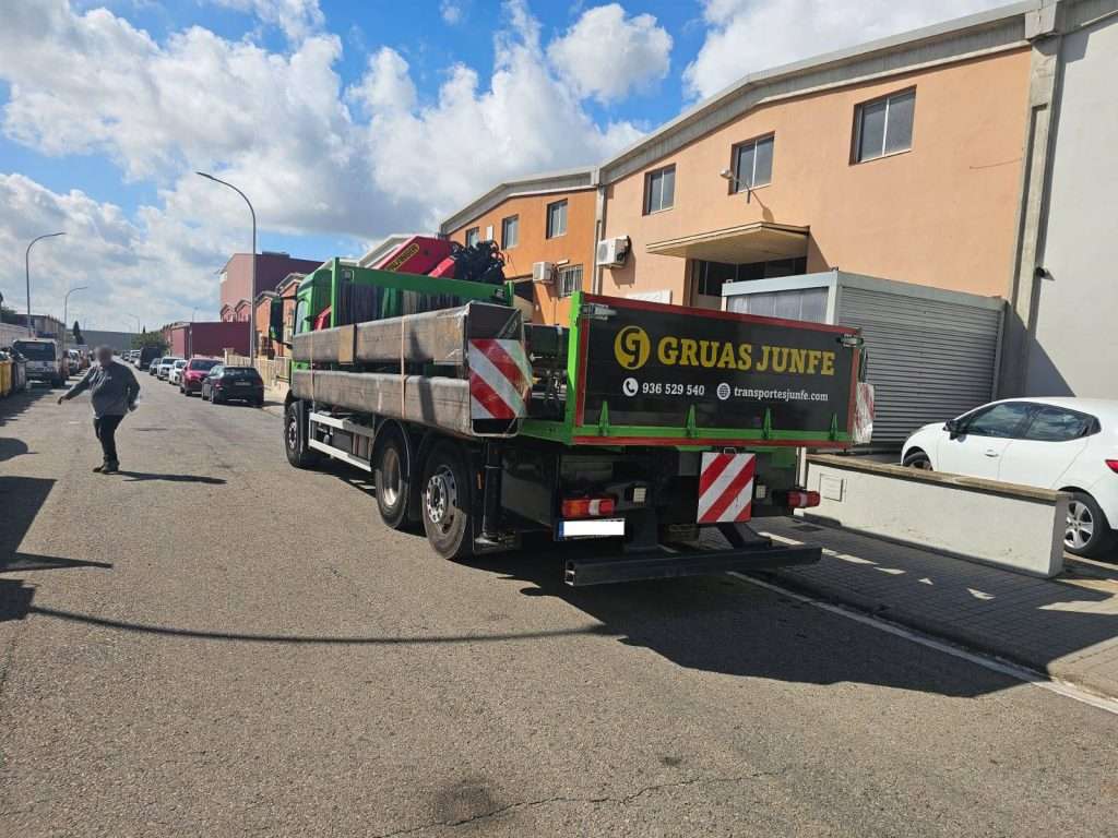 Camión de Grúas Junfe con transporte especial de cargas en polígono industrial.