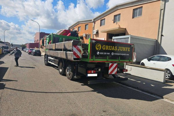 Camión de Grúas Junfe con transporte especial de cargas en polígono industrial.
