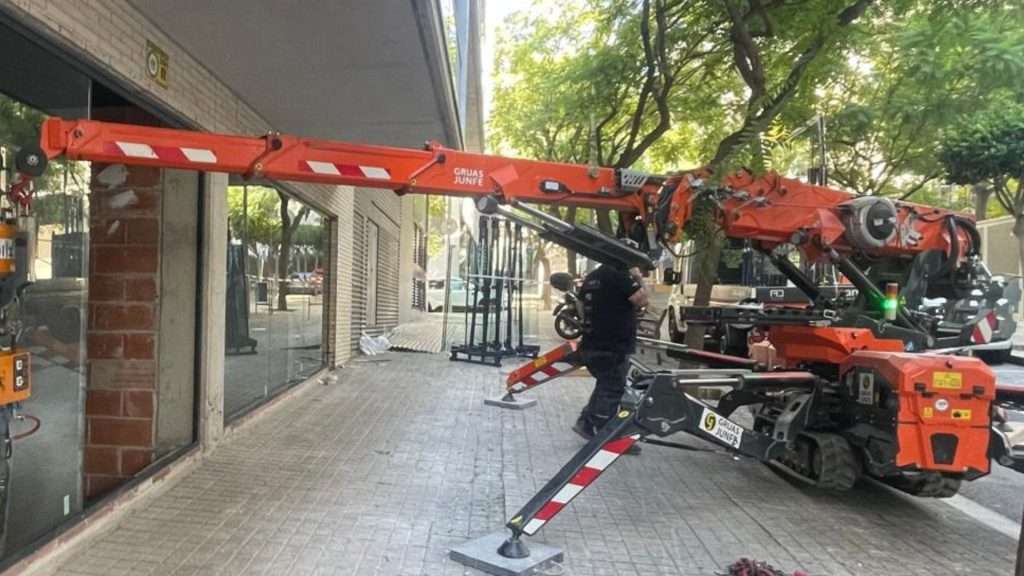 Robot acristalador de Grúas Junfe instalando vidrio en local de Barcelona.