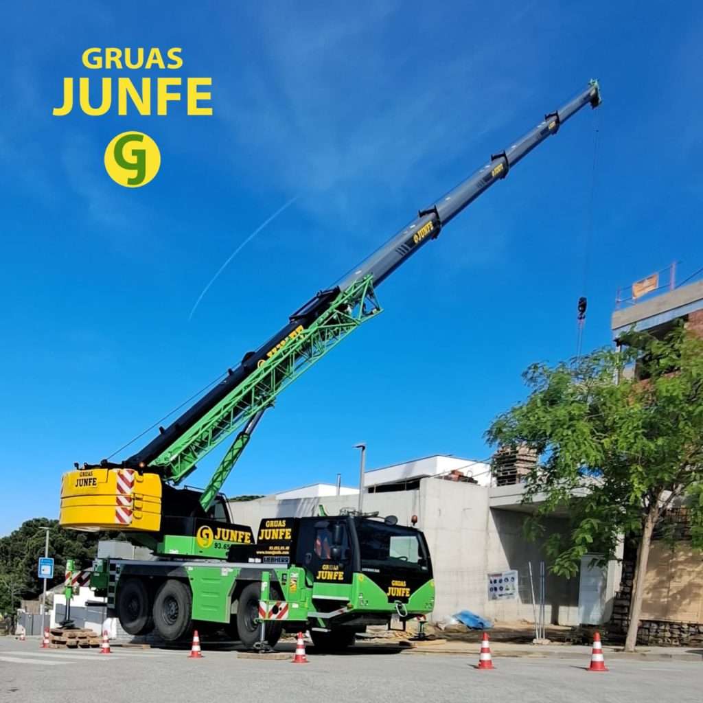 Grúa móvil de Grúas Junfe con pluma extendida en entorno de construcción urbano.