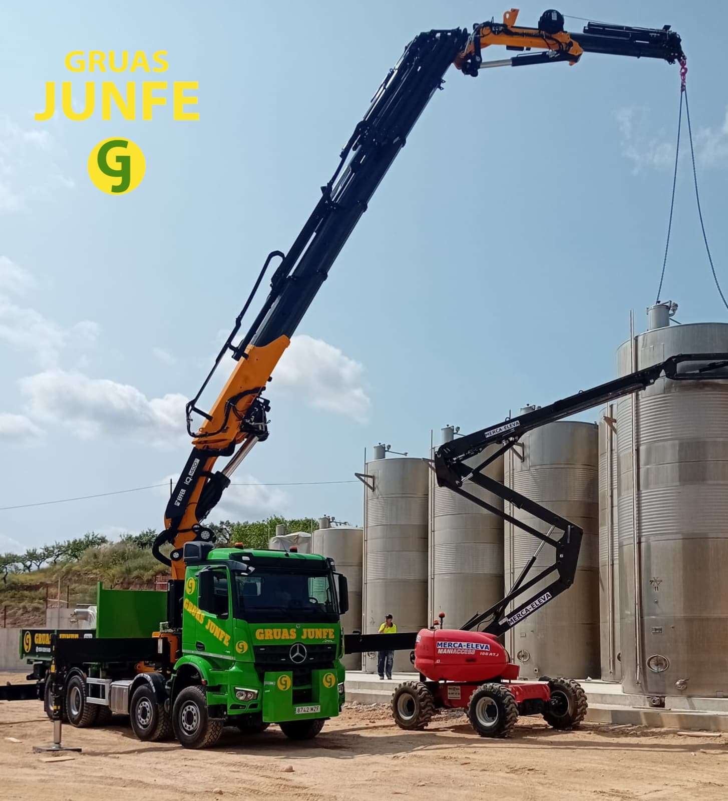 Camión grúa de Grúas Junfe y plataforma elevadora instalando depósitos industriales.